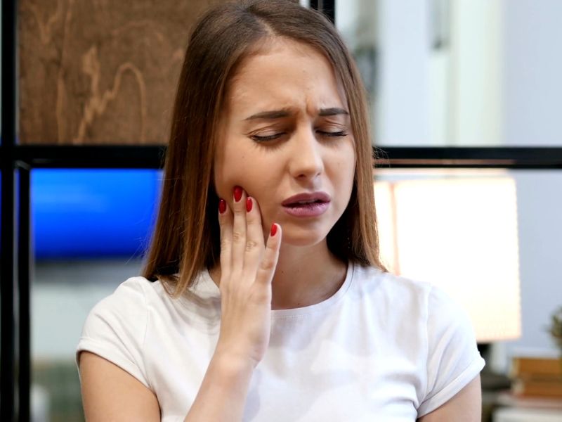 devojka koja pati od zubobolje se drži za vilicu od bola